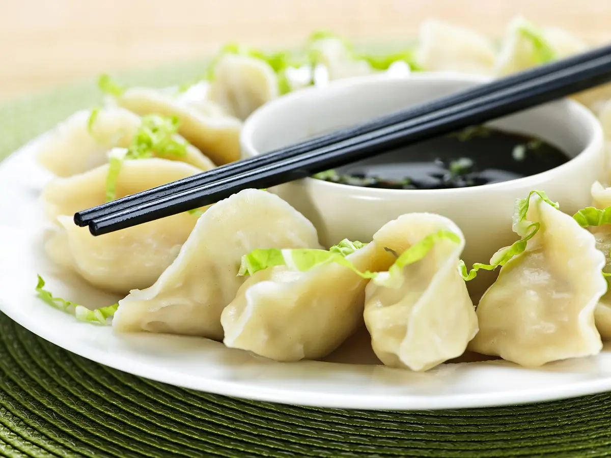 Cheng's-Asian-Cuisine-Asian-Restaurant-Dumpling-Winchester Delicious dumplings on a plate, served with a small bowl of dipping sauce and chopsticks at Cheng's Asian Cuisineļ¼a Asian Restaurant in Winchester